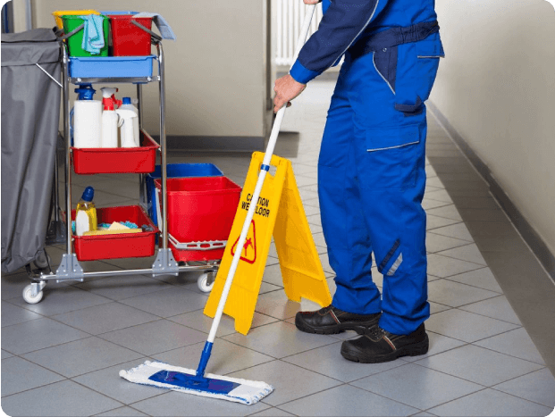 A man in blue and yellow uniform mopping the floor.